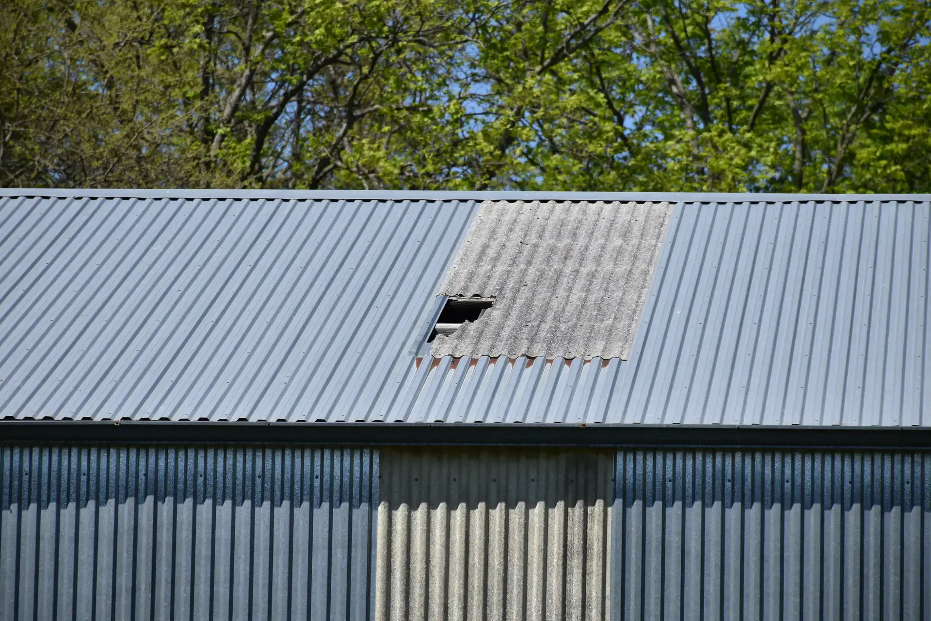 Hole in a steel pole barn roof panel in Minnesota, a storm opening Orton Companies scopes and repairs