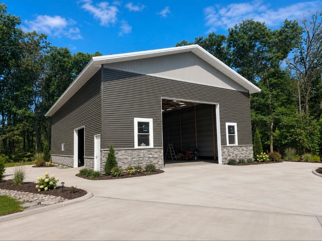 Large gray metal shop building with white trim, open bay doors, and covered porch